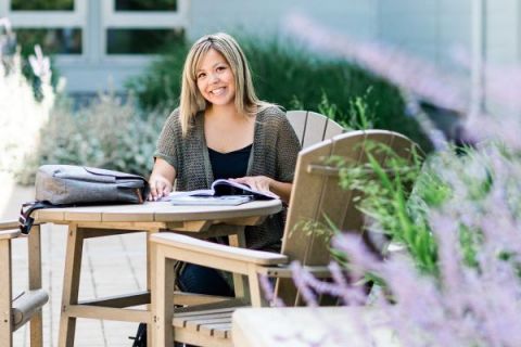 A Business student smiles while studying outside.